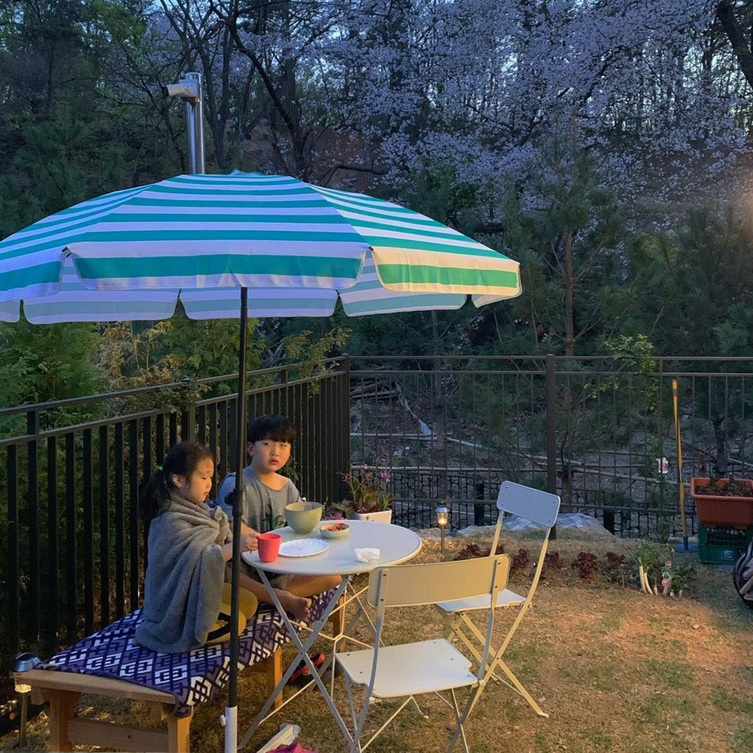 물놀이 후 테라스 파라솔 아래 테이블에서 간식을 먹고 있는 남매 - 삼송자이더빌리지-자이매거진-비욘드아파트먼트