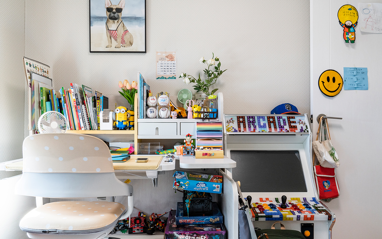 자이매거진-비욘드아파트먼트-장난감과 책들이 가득 놓인 책상과 오락 기계가 있는 아이의 방 인테리어